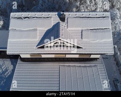 Schneebesen decken Solarpaneele auf einem Hausdach im Winter. Trotz der kühlen Umgebung sind die Photovoltaik-Panels widerstandsfähig. Perfekt für Illustratoren Stockfoto