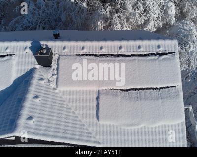 Schneebesen decken Solarpaneele auf einem Hausdach im Winter. Trotz der kühlen Umgebung sind die Photovoltaik-Panels widerstandsfähig. Perfekt für Illustratoren Stockfoto