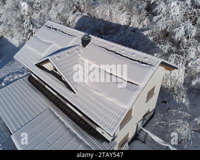 Schneebesen decken Solarpaneele auf einem Hausdach im Winter. Trotz der kühlen Umgebung sind die Photovoltaik-Panels widerstandsfähig. Perfekt für Illustratoren Stockfoto