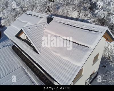 Schneebesen decken Solarpaneele auf einem Hausdach im Winter. Trotz der kühlen Umgebung sind die Photovoltaik-Panels widerstandsfähig. Perfekt für Illustratoren Stockfoto