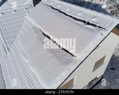 Schneebesen decken Solarpaneele auf einem Hausdach im Winter. Trotz der kühlen Umgebung sind die Photovoltaik-Panels widerstandsfähig. Perfekt für Illustratoren Stockfoto