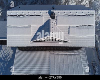 Schneebesen decken Solarpaneele auf einem Hausdach im Winter. Trotz der kühlen Umgebung sind die Photovoltaik-Panels widerstandsfähig. Perfekt für Illustratoren Stockfoto