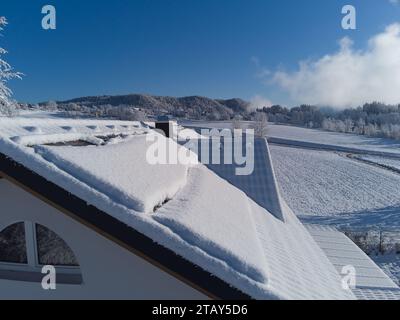 Schneebesen decken Solarpaneele auf einem Hausdach im Winter. Trotz der kühlen Umgebung sind die Photovoltaik-Panels widerstandsfähig. Perfekt für Illustratoren Stockfoto