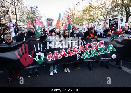 Paris, Frankreich. Dezember 2023. Die Demonstranten halten während der Friedensdemonstration ein riesiges Banner mit der Aufschrift "stoppt das Massaker in Gaza". In Paris kamen mehrere linke Organisationen und die Partei La France Insoumise zusammen, um einen sofortigen Waffenstillstand des israelischen Staates zu fordern und beschuldigten den französischen Präsidenten Emmanuel Macron, an den Massakern in Gaza beteiligt zu sein. Die Demonstration begann am Place de Republique und endete am Place Bastille. Quelle: SOPA Images Limited/Alamy Live News Stockfoto