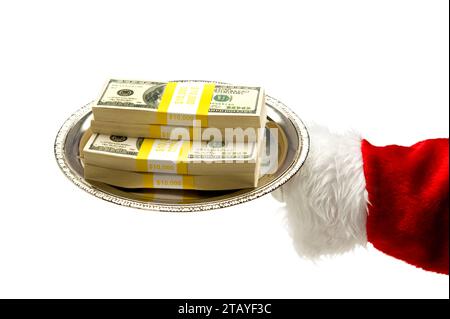 Der Weihnachtsmann hält eine silberne Platte mit einem Stapel von 100 US-Scheinen in 10.000 Bündeln vor weißem Hintergrund Stockfoto