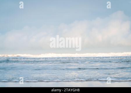 Beobachten Sie die weißen Wellen am Longsands Beach Tynemouth mit Surfern, die an einem eisigen Wintertag mit Schnee am Strand und hellblauem Himmel Wellen fangen. Stockfoto