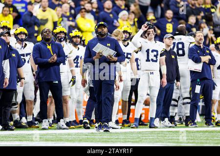 Indianapolis, Indiana, USA. Dezember 2023. Die Angriffskoordinatorin von Michigan, Sherrone Moore, nennt das Spiel von der Seitenlinie während der NCAA-Football-Action zwischen den Michigan Wolverines und den Iowa Hawkeyes im Lucas Oil Stadium in Indianapolis, Indiana. John Mersits/CSM/Alamy Live News Stockfoto