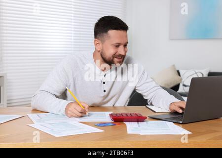 Mann, der Steuern am Tisch im Zimmer macht Stockfoto