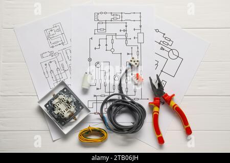 Schaltpläne, Drähte, Zangen und zerlegter Lichtschalter auf weißem Holztisch, Draufsicht Stockfoto