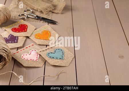 Sackleinen mit Herzen und Schere auf Holztisch, Platz für Text Stockfoto