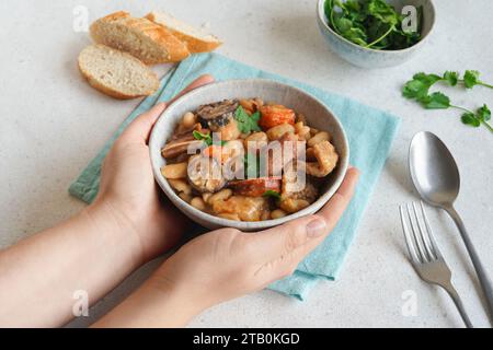 Weibliche Hände halten eine Schüssel mit Kutteneintopf Stockfoto