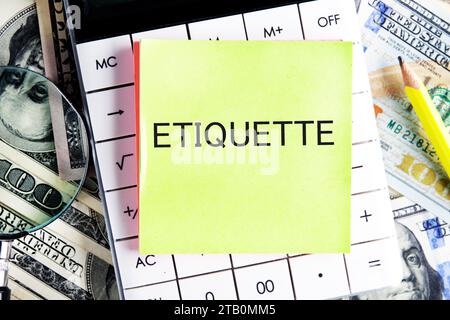 ETIQUETT-Text, ein Wort, das auf einem Aufkleber geschrieben ist und auf einem Rechner vor einem Hintergrund von Geld liegt Stockfoto