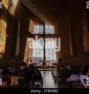 Menschen beten in der berühmten modernen Kapelle des Heiligen Kreuzes mit Altar und Jesus Christus Kruzifix durch großes Glasfenster. Sedona, Arizona Südwesten der USA Stockfoto