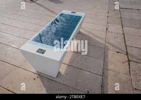 Mit Solarzellen ausgestattete Bank am Strand von mali losinj, die zum Aufladen von Mobiltelefonen und anderen batteriebetriebenen Geräten mit Sonnenenergie verwendet wurde. Ur Stockfoto