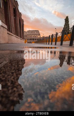 Blick am frühen Morgen auf das kolosseum in rom, mit roten Wolken, die über dem berühmten Amphitheater aufsteigen. Die Sonne geht über dem kolosseum auf, Reflexion i Stockfoto