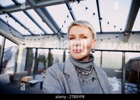Nahaufnahme-Selfie einer modischen Reifen Frau mit schickem, kurzem blondem Haar, faszinierend in elegantem grauen Rollkragen und Jacke, perfekte Kombination aus Elega Stockfoto