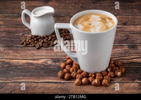 Haselnusslatte in weißem Glas auf Holztisch Stockfoto