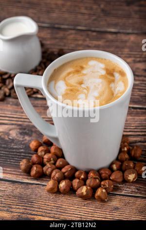 Haselnusslatte in weißem Glas auf Holztisch Stockfoto