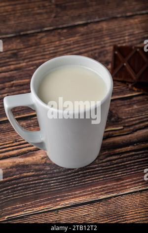 Milch mit Schokolade in schwarzer Tasse auf Holztisch Stockfoto