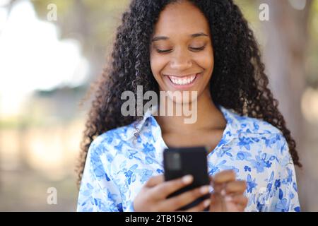 Frontporträt einer glücklichen schwarzen Frau, die im Park telefoniert Stockfoto