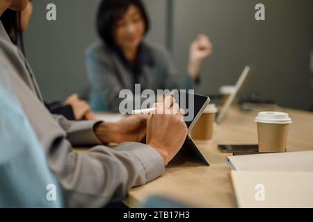 Zugeschnittene Aufnahme einer Geschäftsfrau, die Notizen auf einem digitalen Tablet am Sitzungstisch schreibt Stockfoto