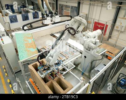 Industrieautomation und Robotik in modernen Industriefabriken. Hochpräziser Roboterarm zur Montage von Holzmöbeln in der Großmöbelherstellung Stockfoto