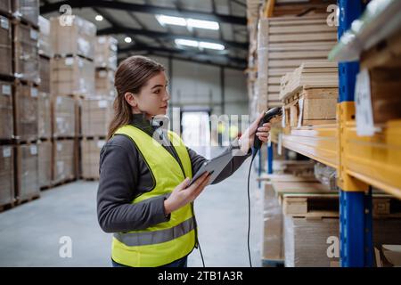 Weibliche Lagerarbeiterin, die einen Scanner hält und die Barcodes auf Produkten im Lager scannt. Lagermanager, der das Lagerscansystem verwendet. Stockfoto