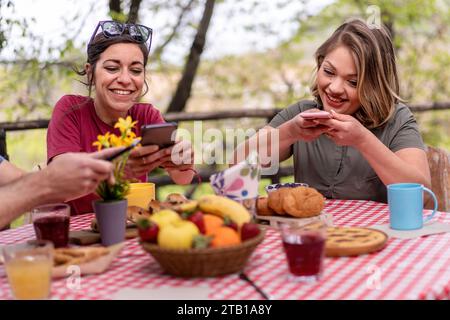 Zwei Frauen genießen es, ihren lebhaften Brunch auf Smartphones festzuhalten und die kulinarische Kultur zu genießen. Stockfoto