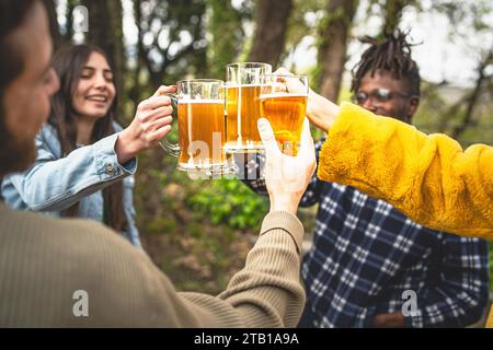 Verschiedene Freunde stoßen mit Biergläsern im Freien an und feiern gemeinsam einen fröhlichen Moment. Stockfoto