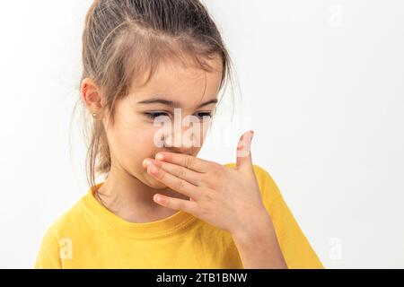 Das kleine Schulmädchen fühlt sich schlecht und riecht nicht, isoliert auf weißem Hintergrund. Stockfoto