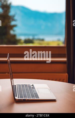 Laptop-Computer auf Wohnzimmer Schreibtisch am Fenster mit wunderschönem Blick auf die Sommerlandschaft, selektiver Fokus Stockfoto