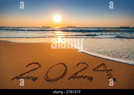 Happy New Year 2024 Konzept, Schriftzug am Strand. Sonnenaufgang auf dem Meer. Stockfoto