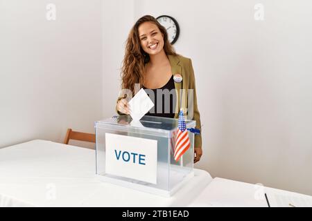 Junge schöne hispanische Frau Wahltisch Präsident Putting Abstimmung in Box an Wahlhochschule Stockfoto
