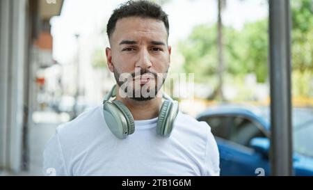Junger arabischer Mann mit Kopfhörern auf der Straße Stockfoto
