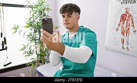 Attraktiver junger hispanischer Mann, der als Physiotherapeut in der Reha-Klinik arbeitet und sich an ernsthaften Videogesprächen über die Genesungsreise des Patienten beteiligt Stockfoto