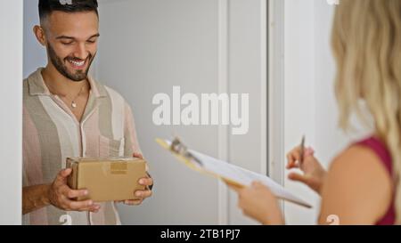 Junger hispanischer Mann, der Paketunterschrift auf der Straße erhält Stockfoto