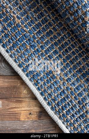 Handgewebter Teppich mit geometrischem Denim-Bereich auf Holzboden. Stockfoto