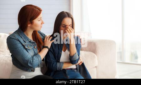 Nahaufnahme Foto von zwei Freundinnen auf der Couch zu Hause, ein Mädchen beruhigt ihre Freundin. Bruch in der Beziehung Stockfoto