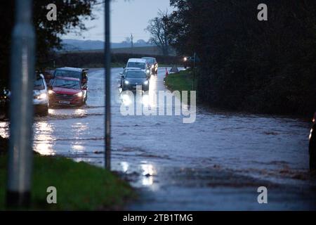 Überschwemmung entlang der Woodbury Road, Exeter, Großbritannien während der morgendlichen Hauptverkehrszeit, mit Autos, die langsam um die Flut fahren Stockfoto