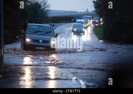 Überschwemmung entlang der Woodbury Road, Exeter, Großbritannien während der morgendlichen Hauptverkehrszeit, mit Autos, die langsam um die Flut fahren Stockfoto