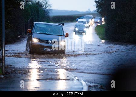 Überschwemmung entlang der Woodbury Road, Exeter, Großbritannien während der morgendlichen Hauptverkehrszeit, mit Autos, die langsam um die Flut fahren Stockfoto