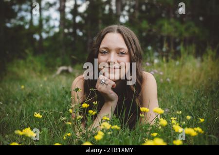 Junges lächelndes Teenager-Mädchen, das im Blumenfeld liegt Stockfoto