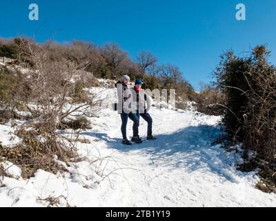 Frau und Kind mit Schaufel, die auf dem Hintergrund der Winterberge steht Stockfoto