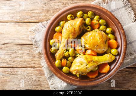 Tajine zitoun ist ein traditionelles algerisches Gericht, das aus einer Kombination von Hühnerstücken, Oliven, Zwiebeln und Karotten aus nächster Nähe auf einem Holztisch zubereitet wird. Horizontal t Stockfoto