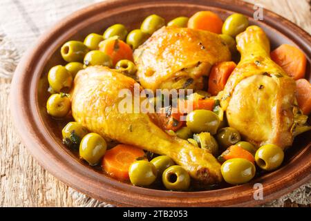 Tajine zitoun ist ein traditionelles algerisches Gericht, das aus einer Kombination von Hühnerstücken, Oliven, Zwiebeln und Karotten aus nächster Nähe auf einem Holztisch zubereitet wird. Horizontal Stockfoto