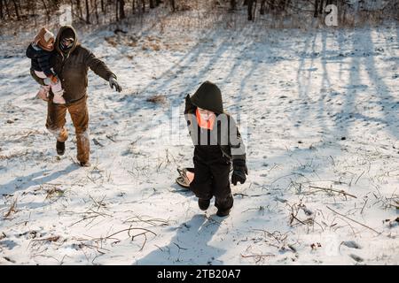 Familie, die im Winter den Schlittenberg hinaufläuft Stockfoto