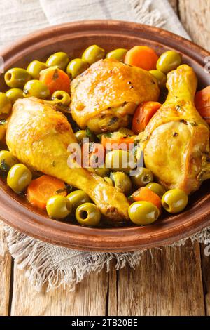 Traditionelles algerisches Essen Tajine Zitoune aus Hühnchen, Karotten und grünen Oliven in Nahaufnahme auf Holztisch. Vertikal Stockfoto