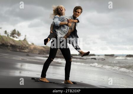 Fröhlicher Mann huckepack Frau, während am Ufer stehend Stockfoto