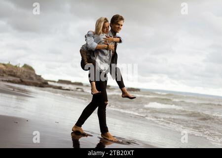 Fröhlicher Mann huckepack Frau, während am Ufer stehend Stockfoto