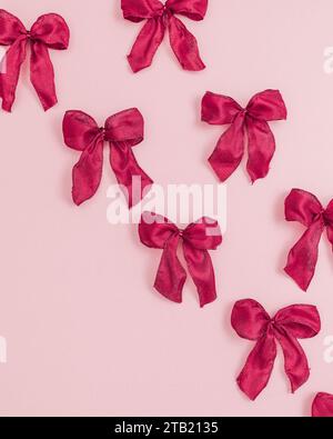 Kleine rote Bögen auf rosafarbenem Hintergrund Stockfoto